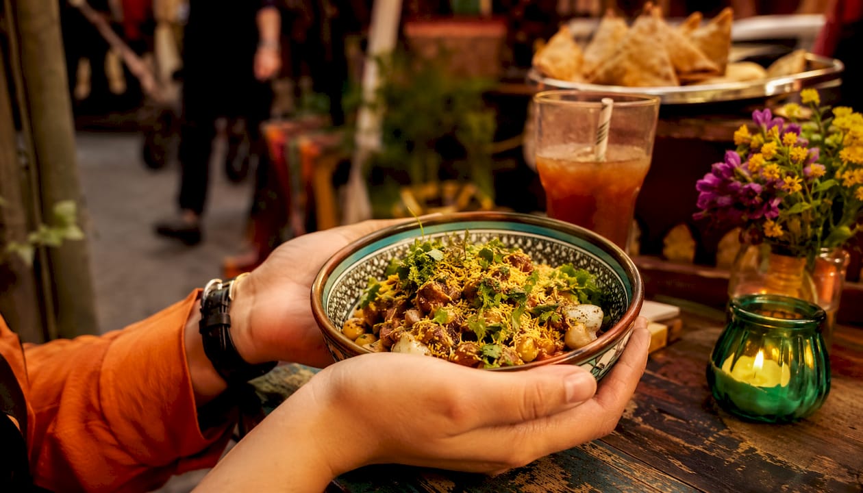Unas manos sostienen un cuenco lleno de chaat, el popular aperitivo callejero de la India.