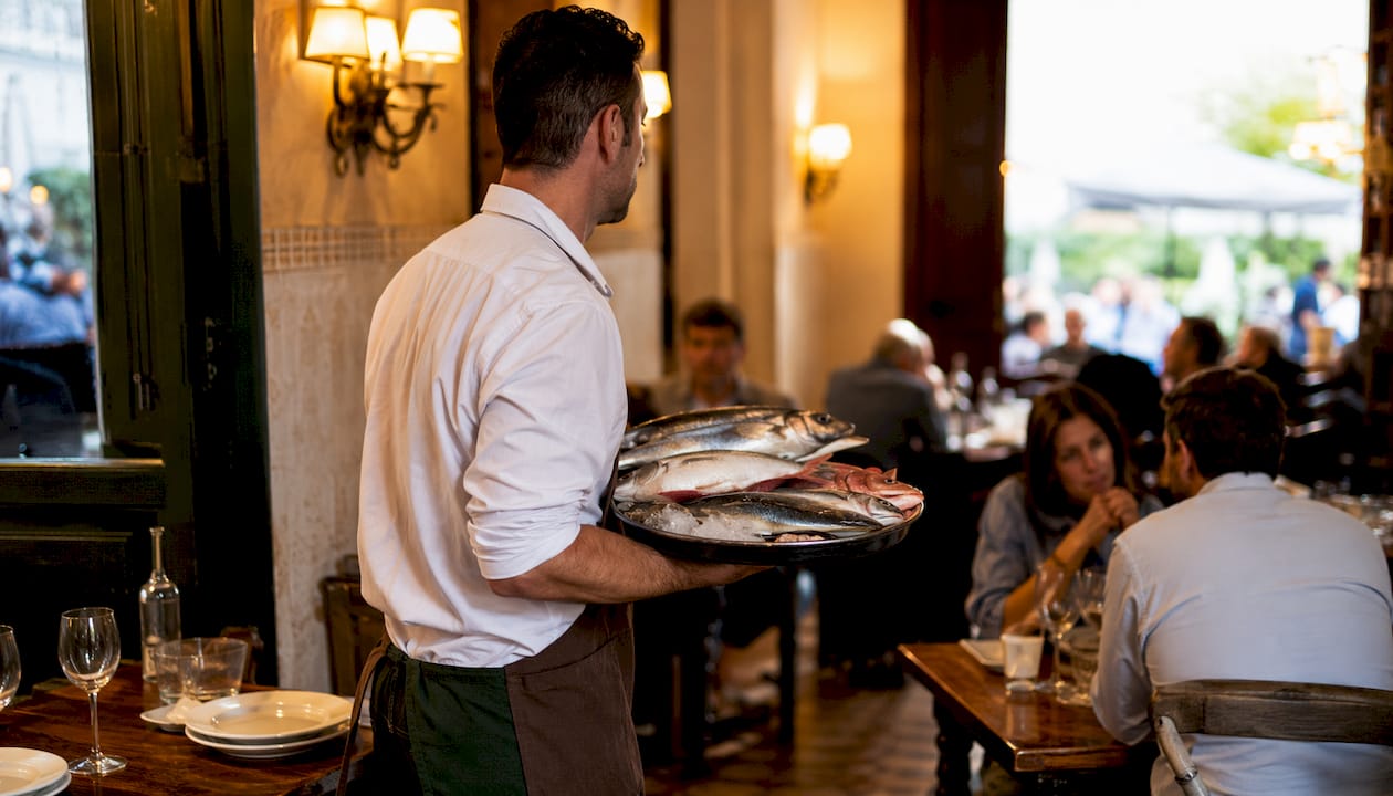 Waiter serving fresh fish in Barcelona