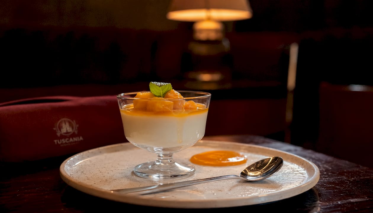 Panna cotta acompañada de coulis y servida con una elegante cuchara de plata