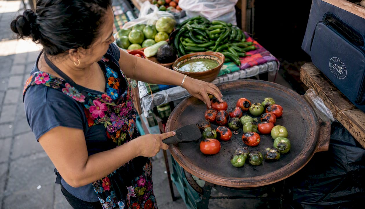 Asando jitomates y tomatillos en el comal para darles ese sabor ahumado típico de la cocina mexicana.
