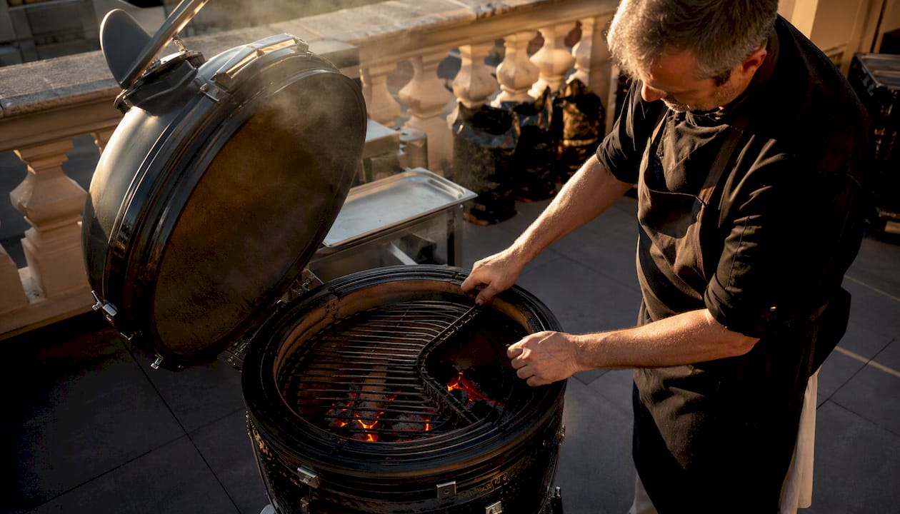 El chef regula la intensidad del fuego indirecto en la parrilla de carbón.
