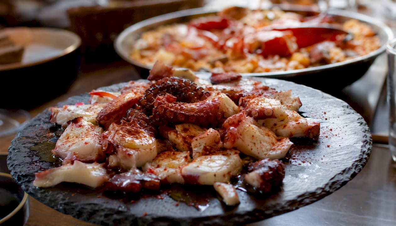 Detalle en primer plano de un plato de pulpo a feira junto a una sabrosa arroz con bogavante.