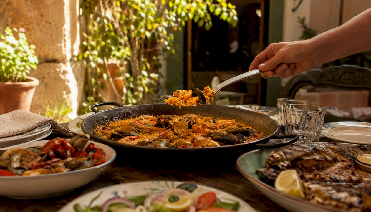 Mesa mediterránea repleta de paella y platos típicos para el almuerzo