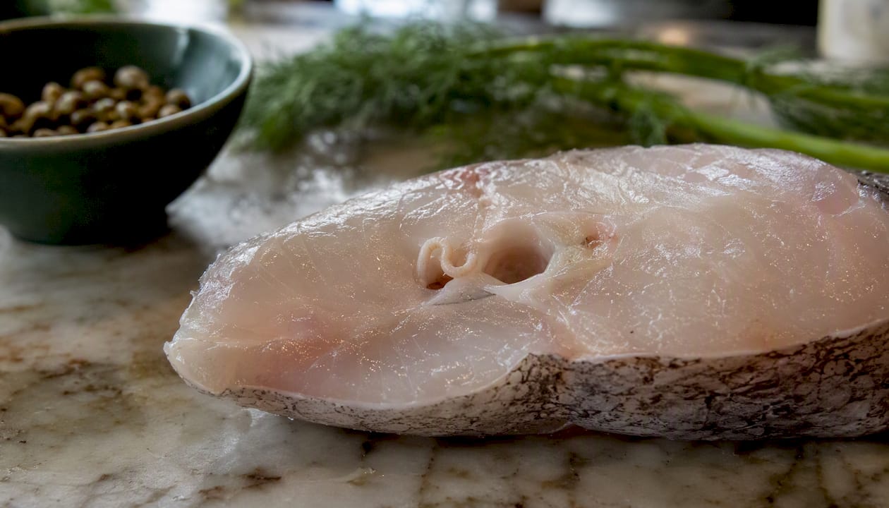 Close-up of raw fish slice showing Anisakis larvae