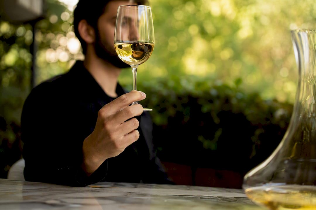 Un sumiller examina atentamente el color del vino en su copa durante una cata.