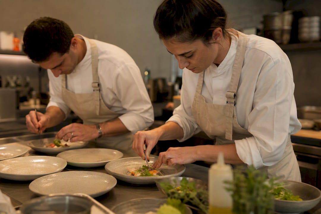 El equipo de cocina se encarga de emplatar cuidadosamente los platos antes de que salgan al comedor.
