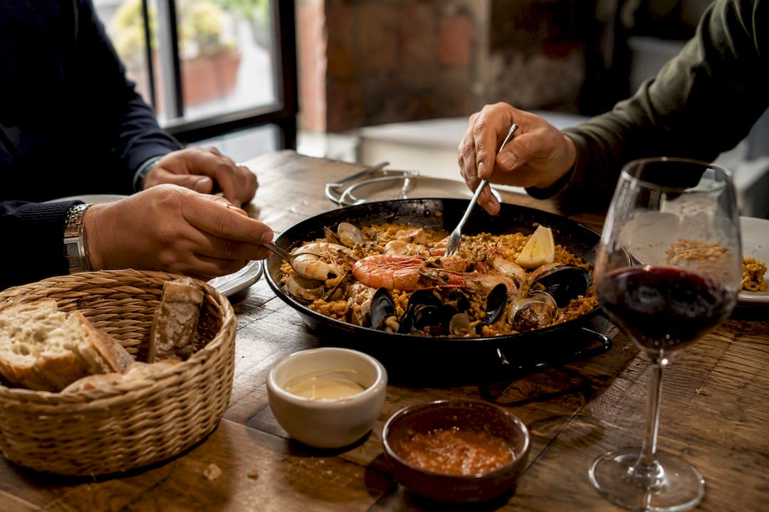 Una pareja disfruta de un plato mediterráneo compartido en el centro de la mesa.