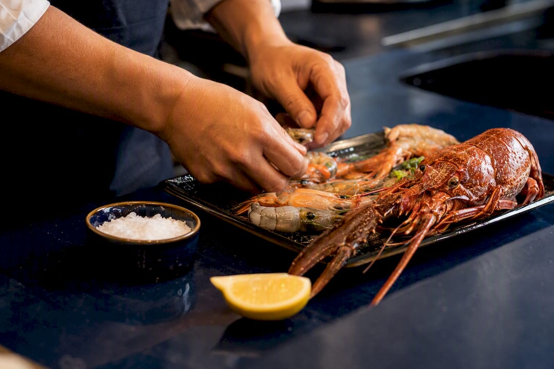 Unas manos limpian mariscos frescos sobre una encimera oscura.