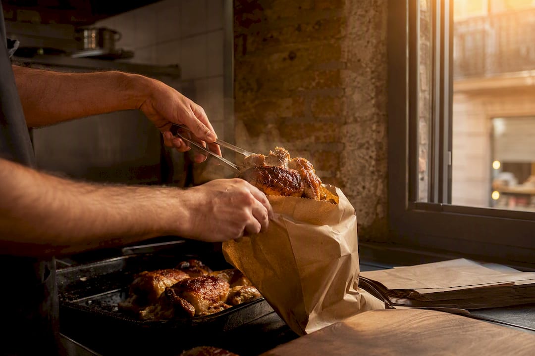 Manos cerrando la bolsa de entrega para un pedido de pollo a l’ast