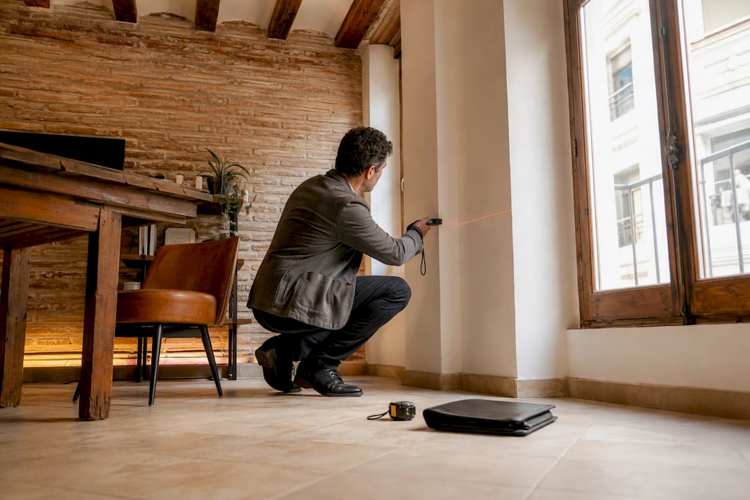 Tasador midiendo una pared en un apartamento de Valencia