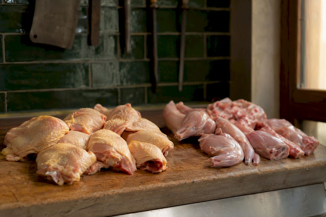 Fresh chicken thighs and rabbit cuts on board