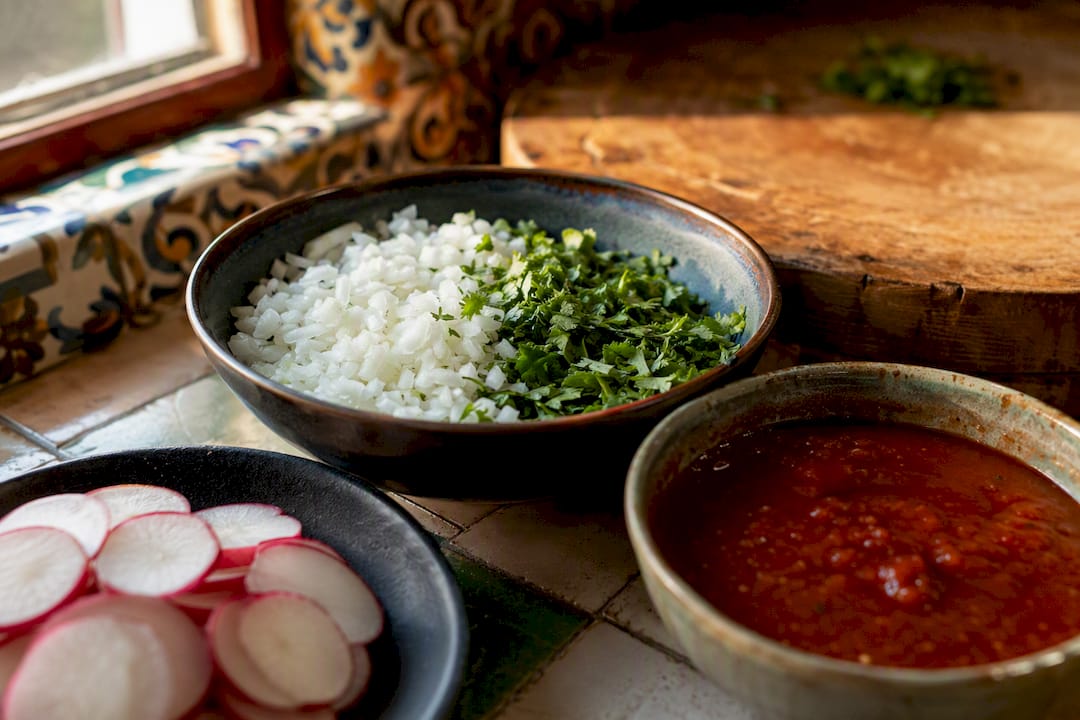 Guarniciones de cebolla, cilantro, rábano y salsa roja para tacos de bistec