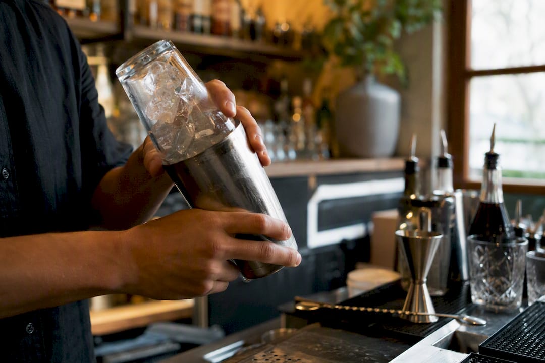 Bartender agitando cóctel margarita con hielo grande
