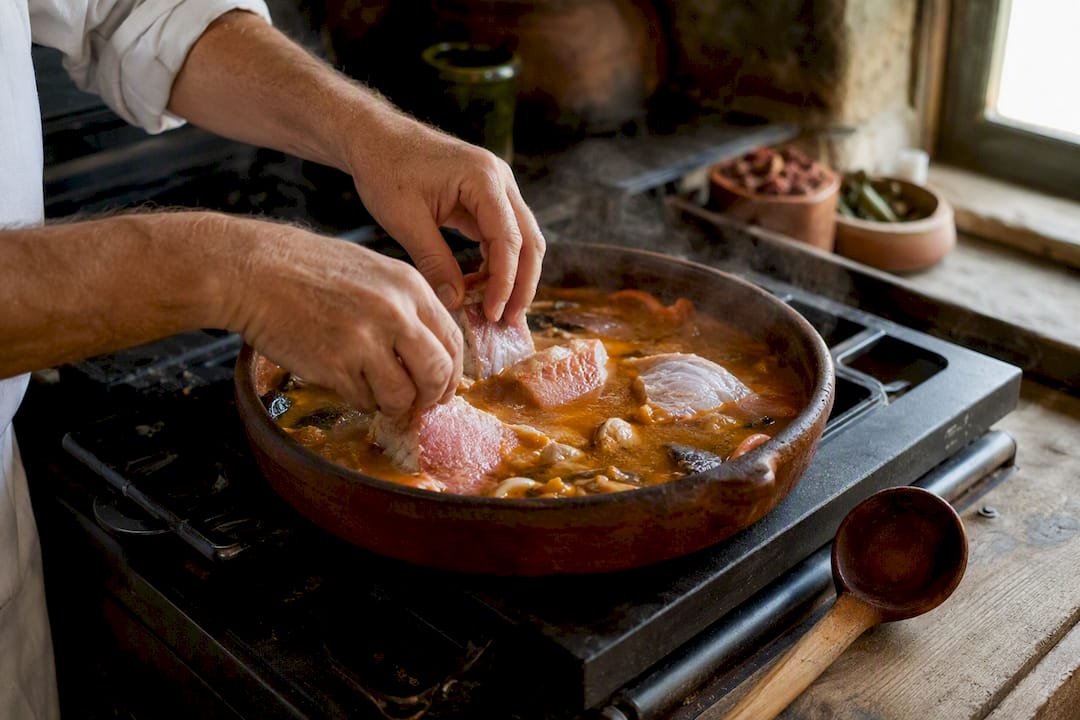 Chef adding fish to suquet broth