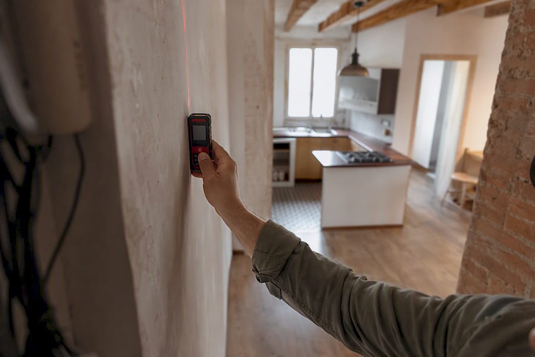 Tasador midiendo la pared de un departamento