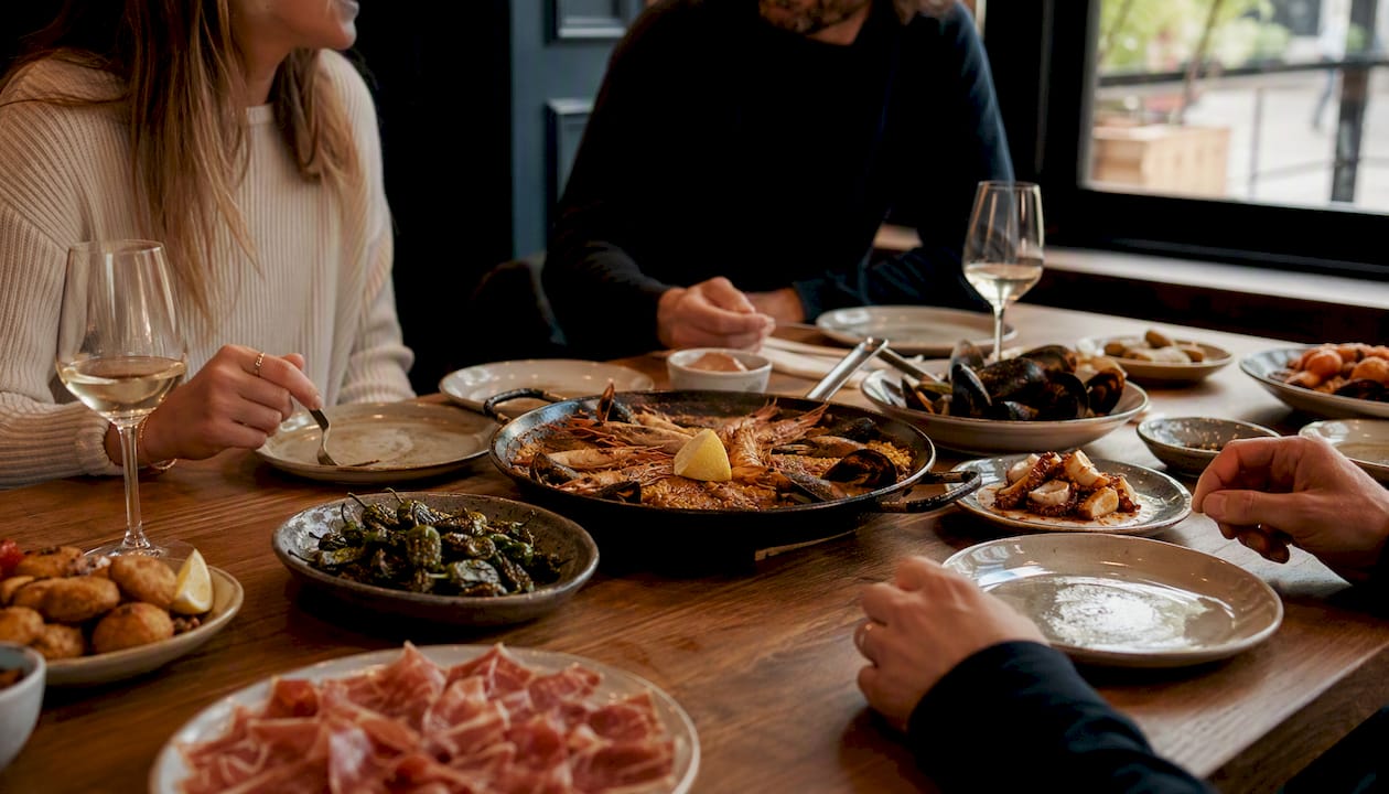 Mesa preparada para grupo con tapas para compartir y paella