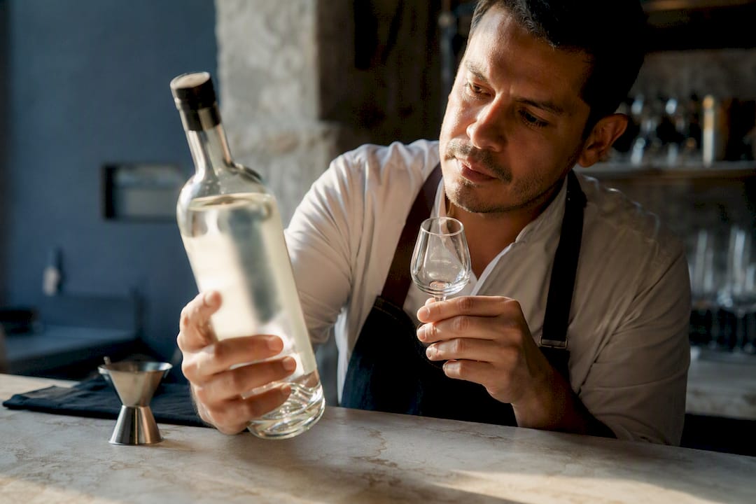 Mano revisando la etiqueta de una botella de mezcal