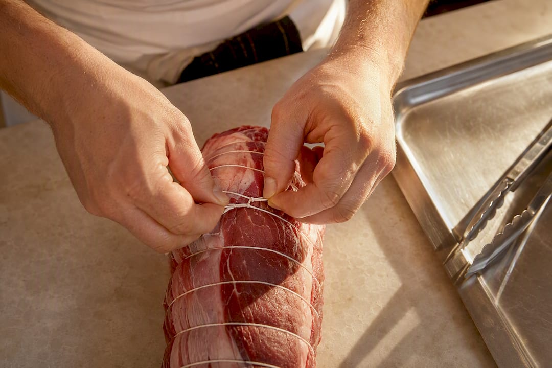 Manos atando una pieza de carne