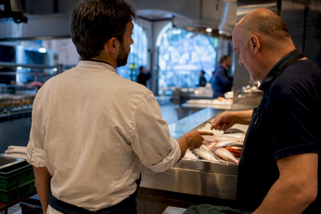 Chef consulting fishmonger over morning catch