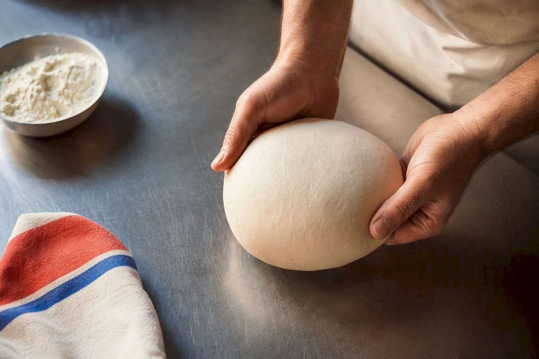 Manos formando una bola de masa para pizza napolitana