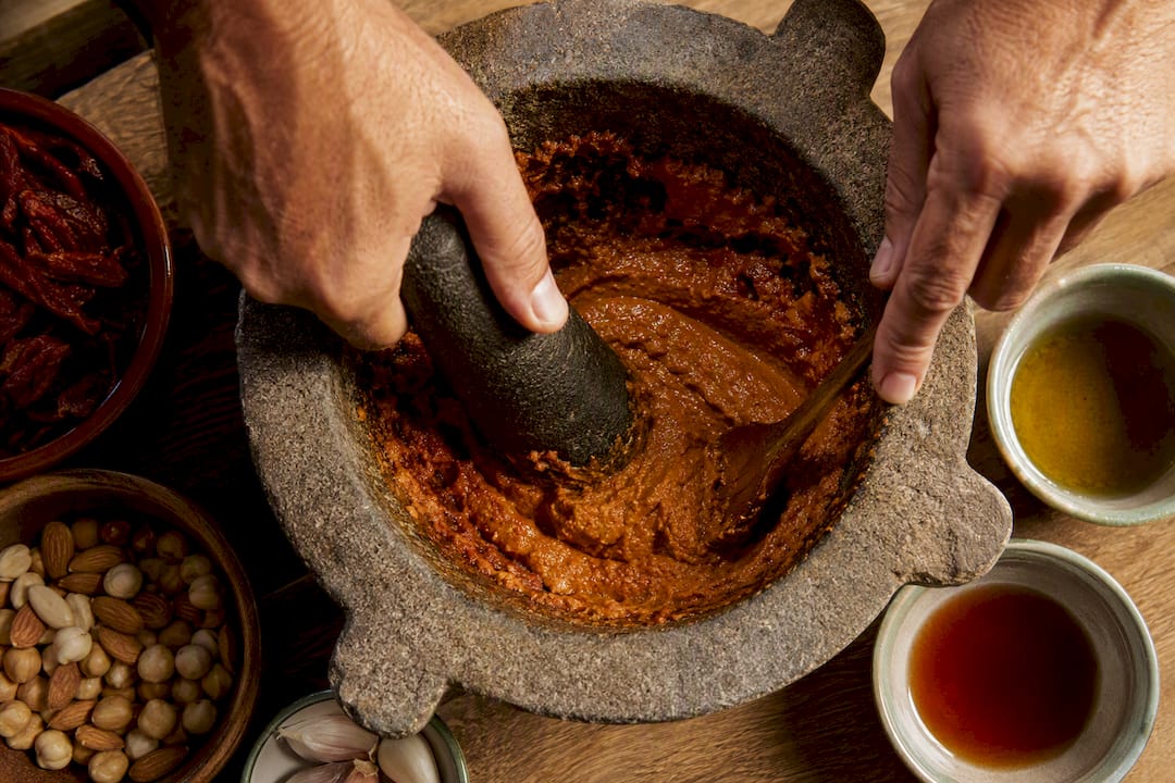 Hands grinding ingredients for xató sauce