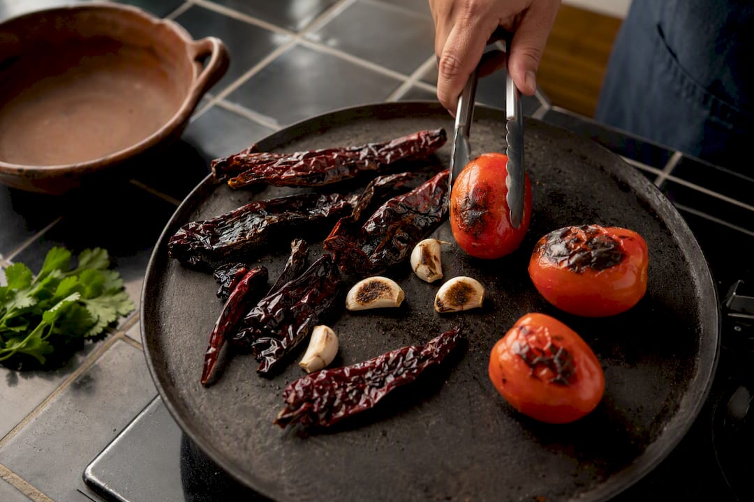 Chiles, jitomates y ajo asados en un comal