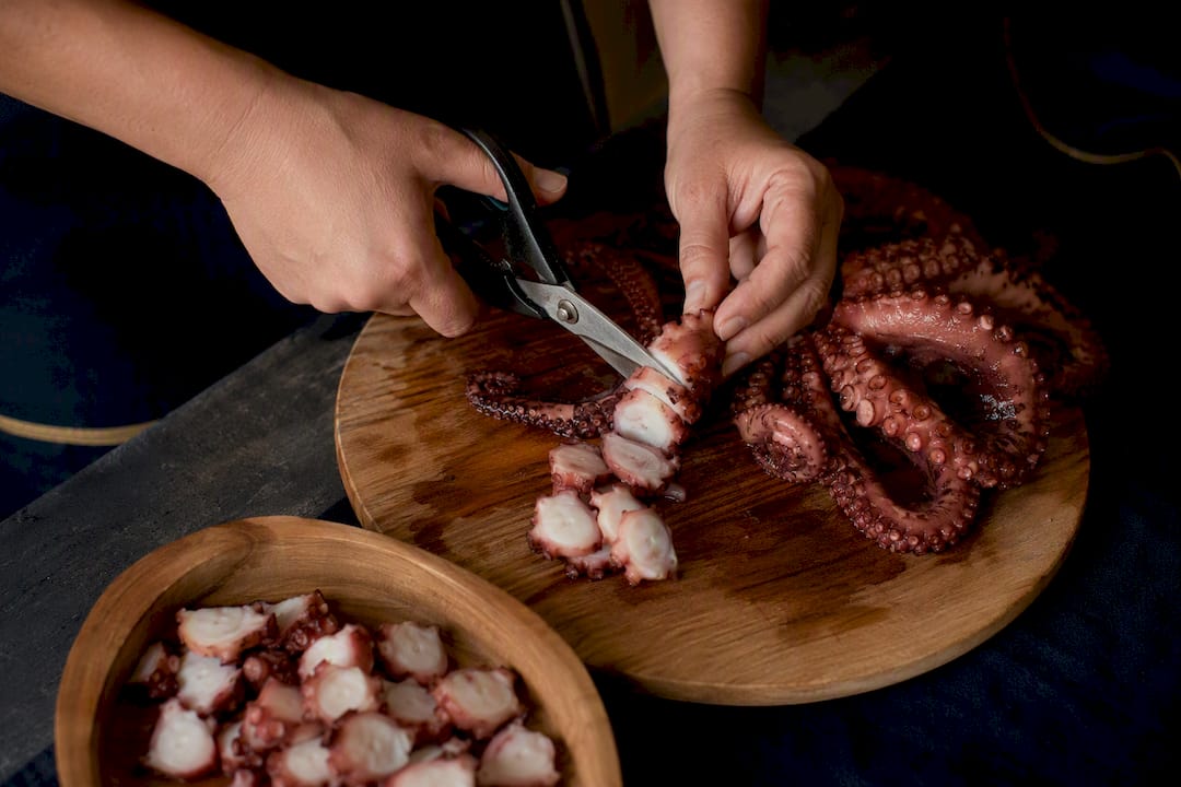 Pulpeira cortando pulpo cocido con tijeras