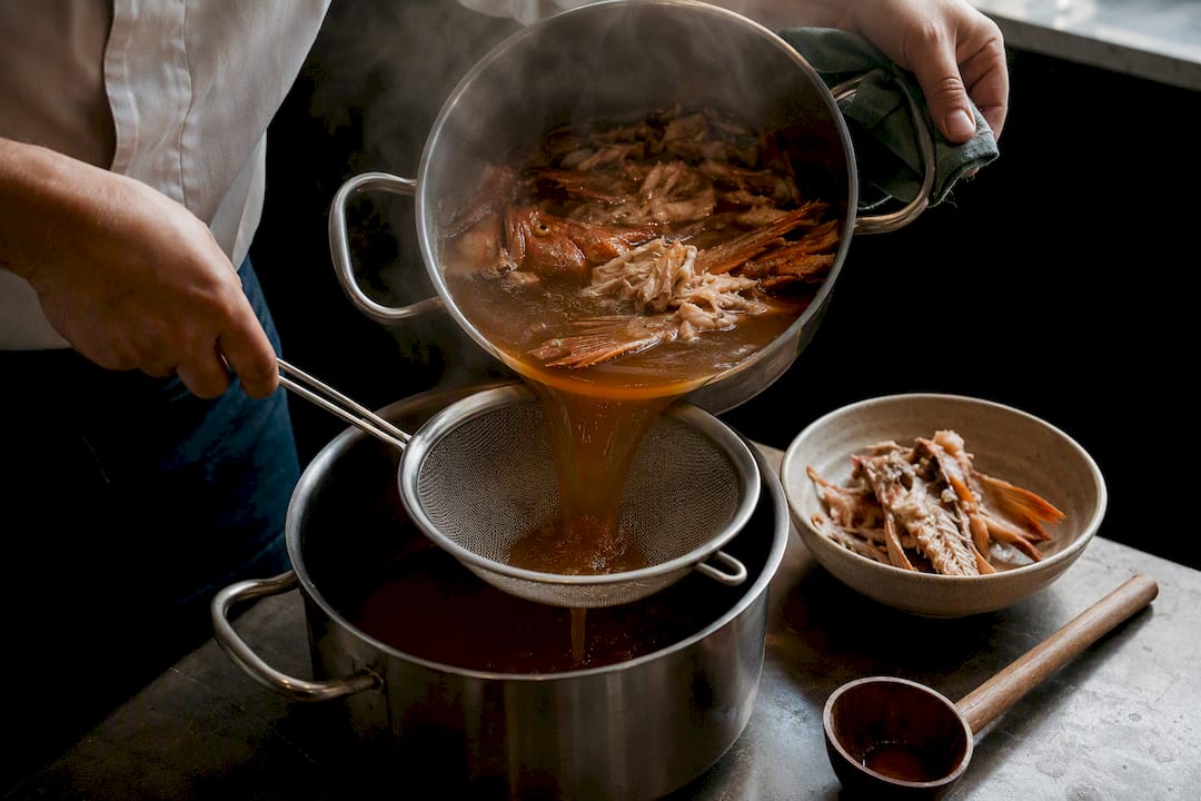 Fish fumet being strained into pot