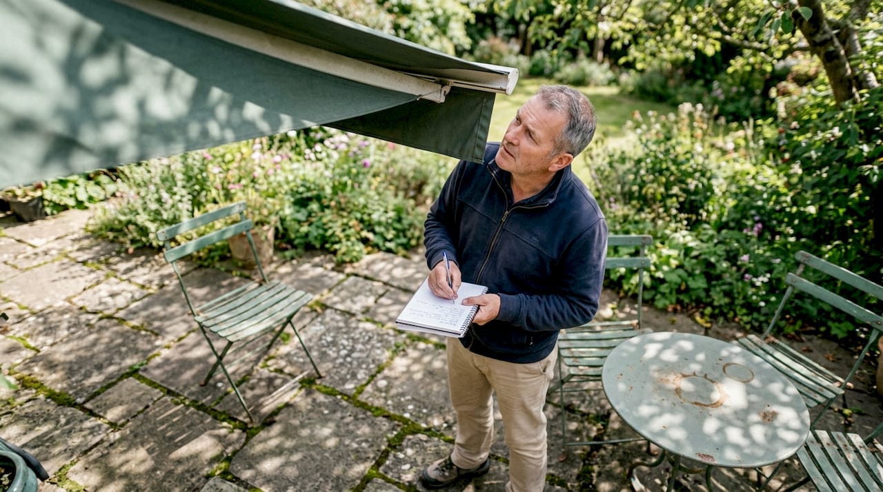 Man inspecting awning fabric on patio