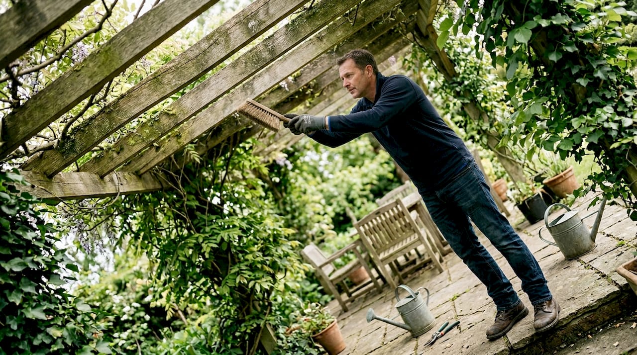 Worker cleaning timber slatted pergola roof