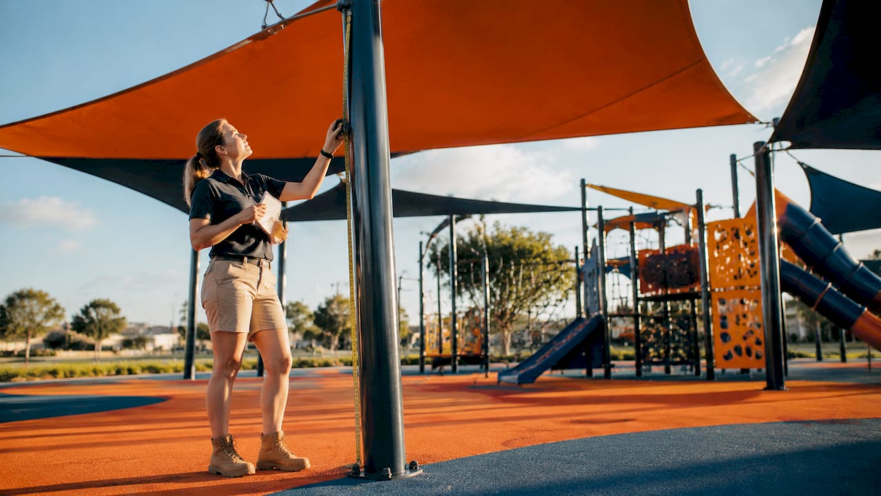 Woman inspecting shade sails in playground
