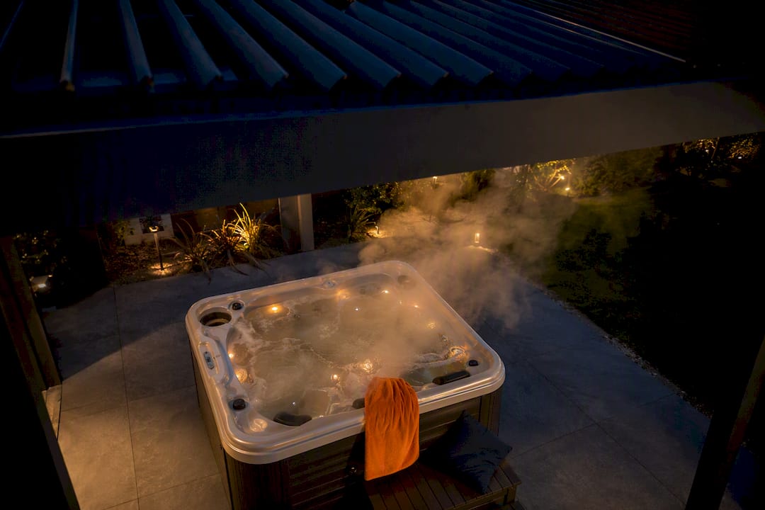 Steaming hot tub beneath ventilated pergola