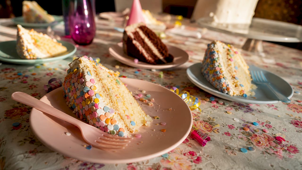 Mesa de festa recheada de bolos decorados com folhas de hóstia coloridas