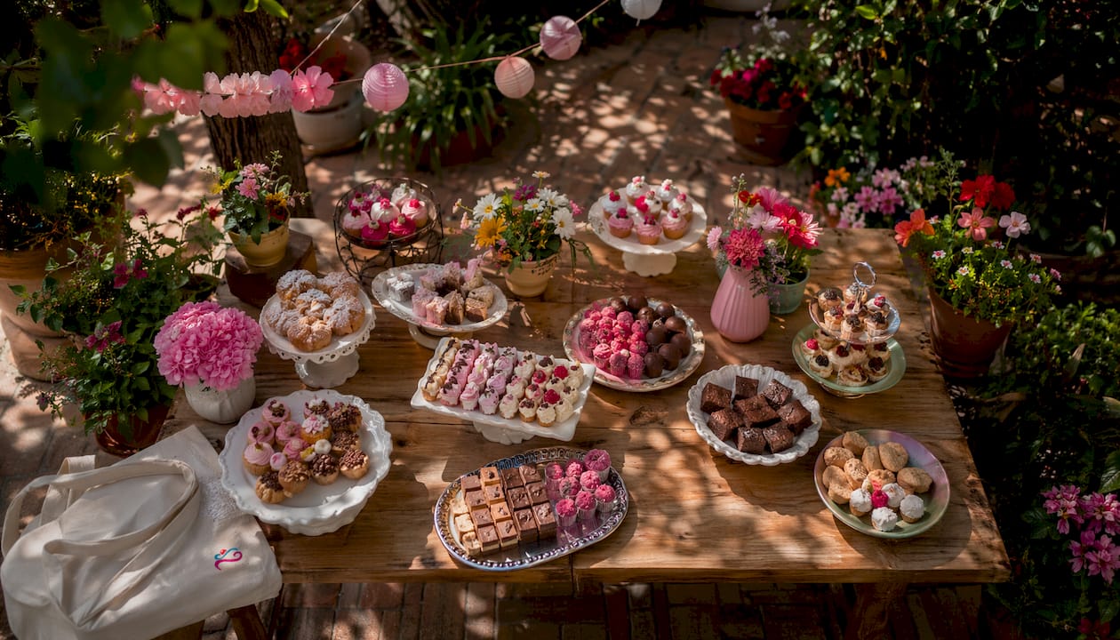 Mesa de postres presentada en diferentes alturas, decorada con una variedad de dulces irresistibles.