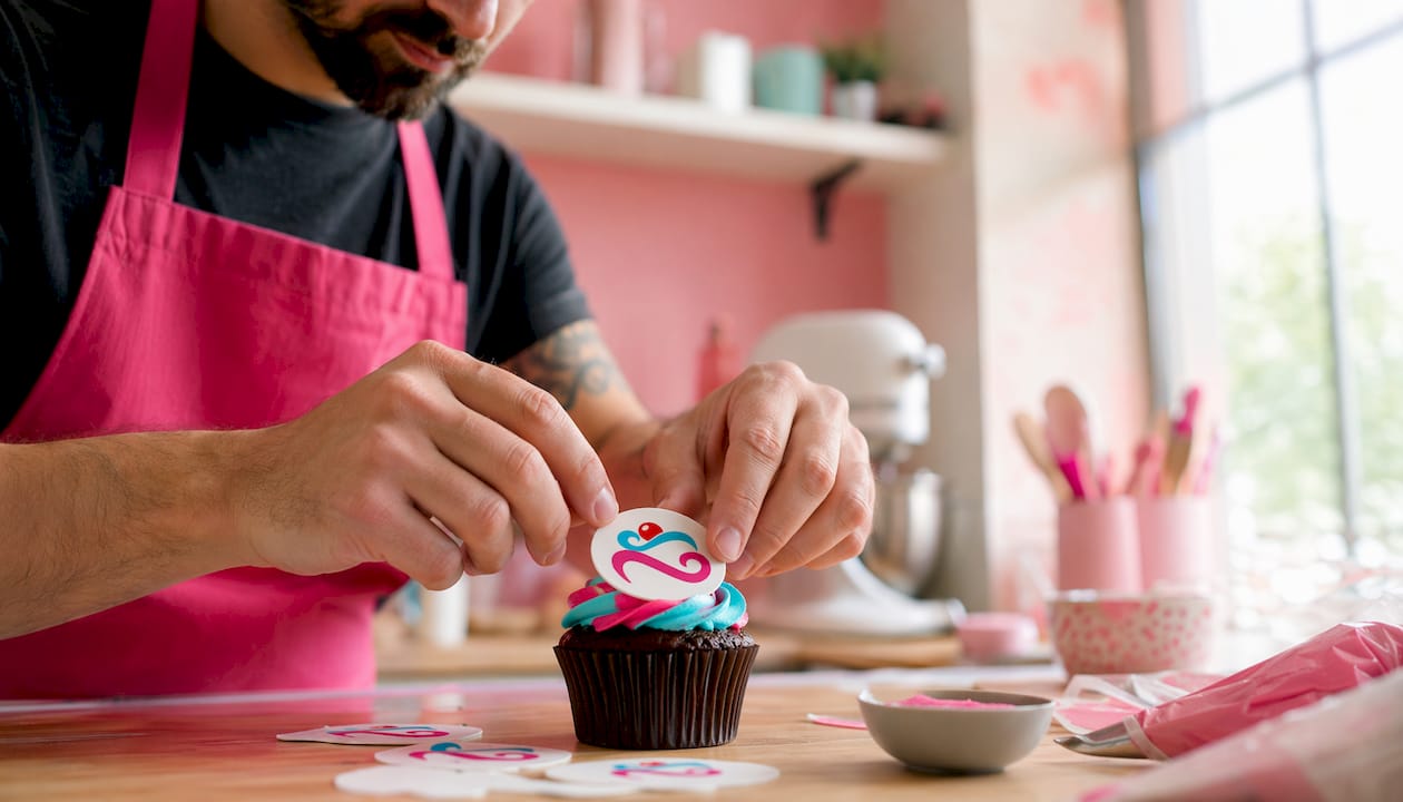 Unas manos decoran un pastel colocando una oblea personalizada por encima.