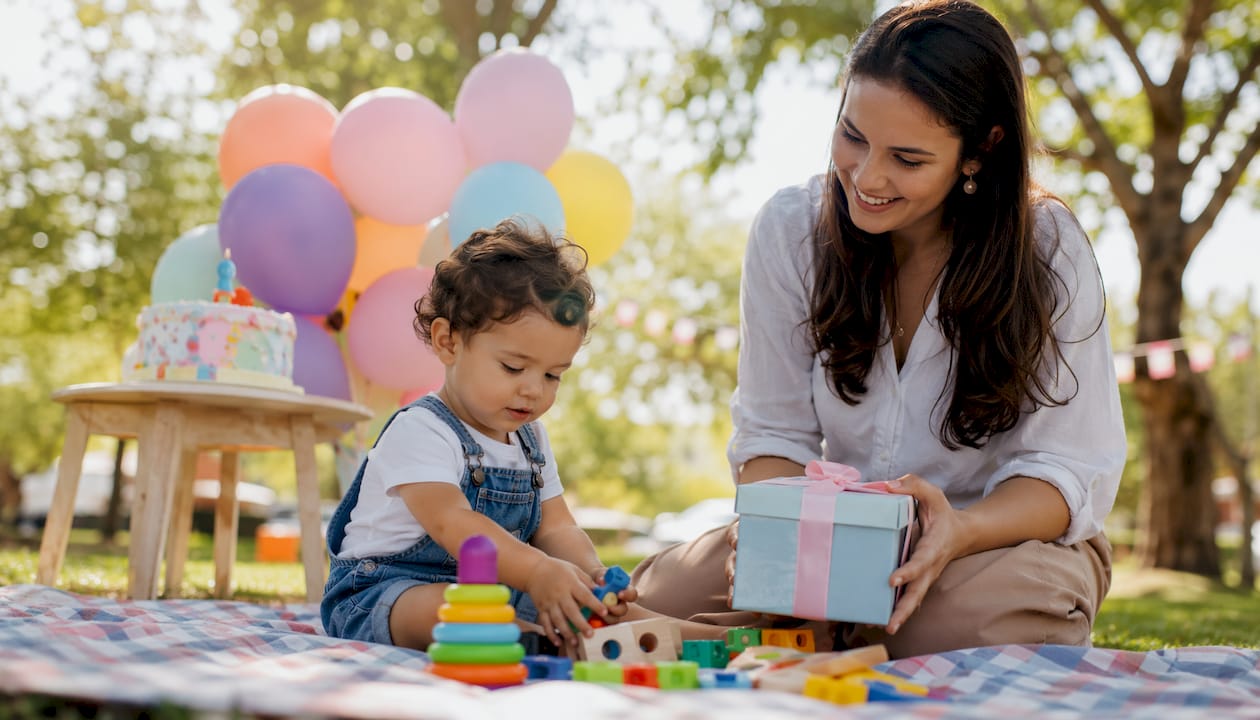 Uma criança pequena a divertir-se com os novos brinquedos de aniversário na sala de estar.