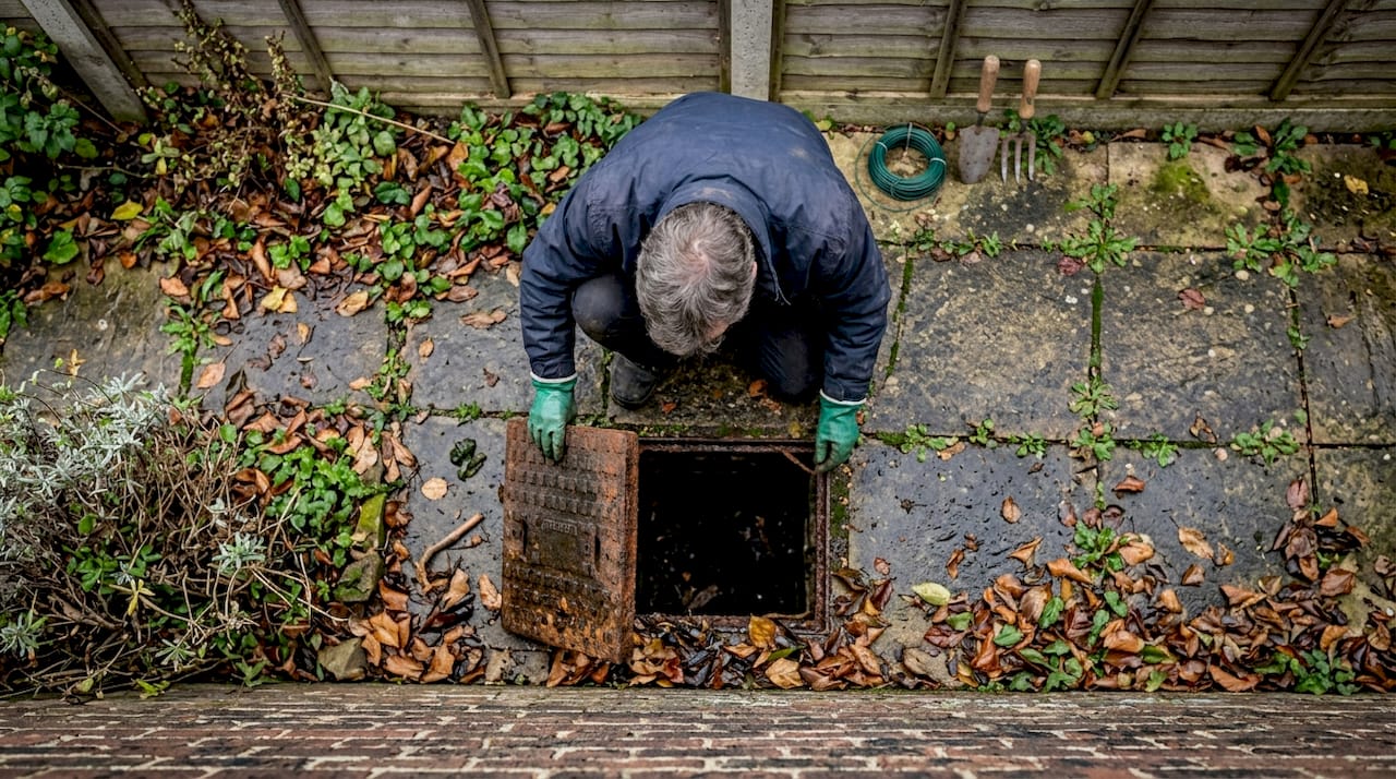 Person inspecting outdoor ground-level drain