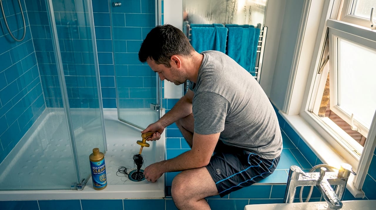 Man removing hair clog from shower drain