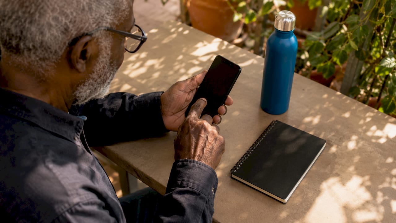 Man typing password on smartphone in park