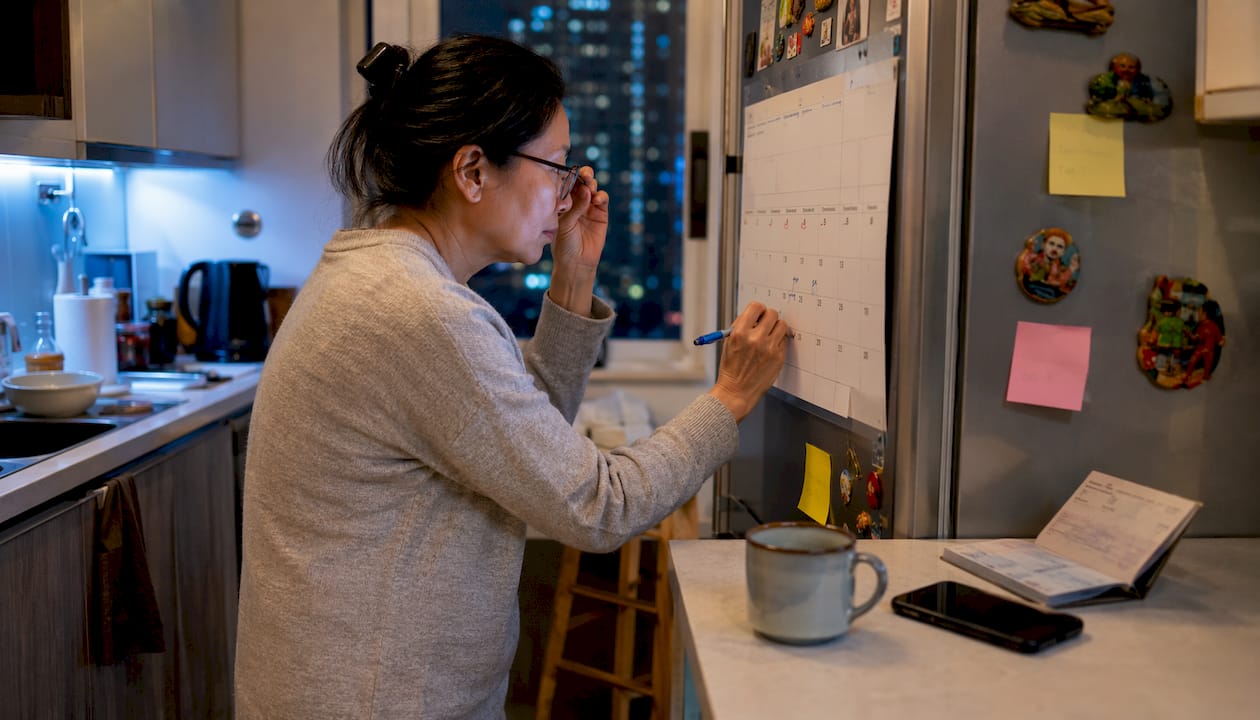 Woman marking passport renewal on wall calendar