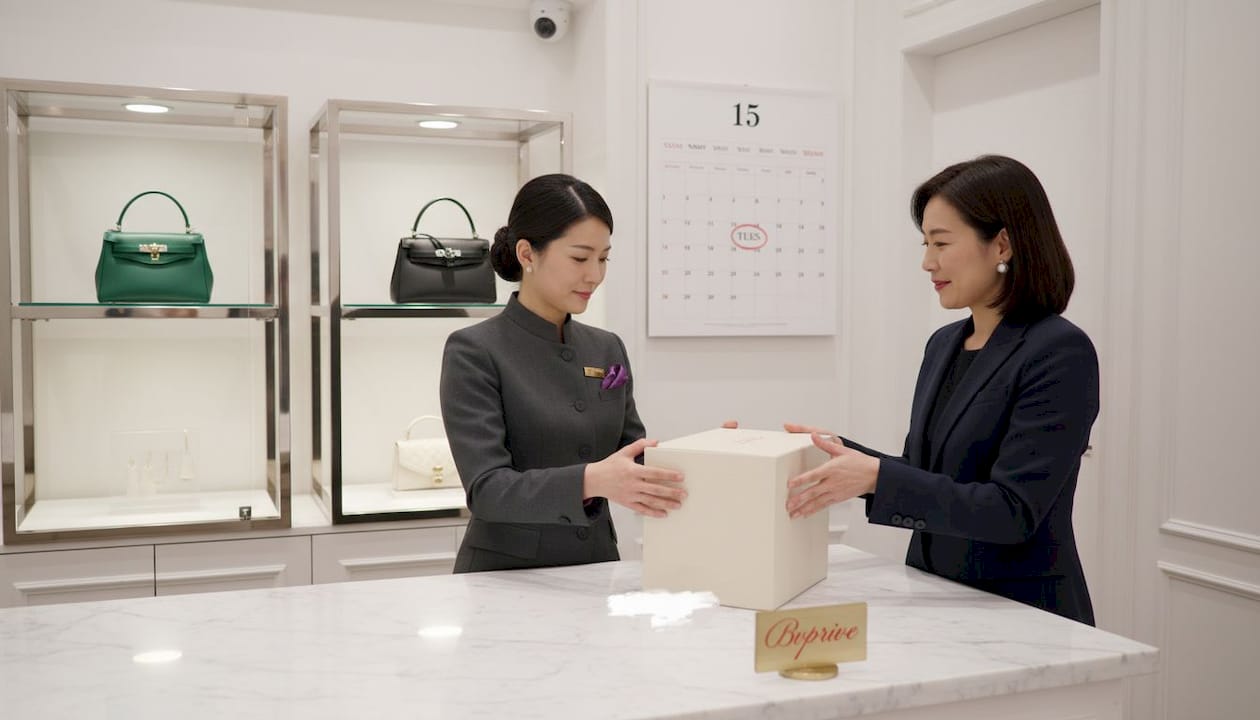 Sales associate hands boxed designer bag to client