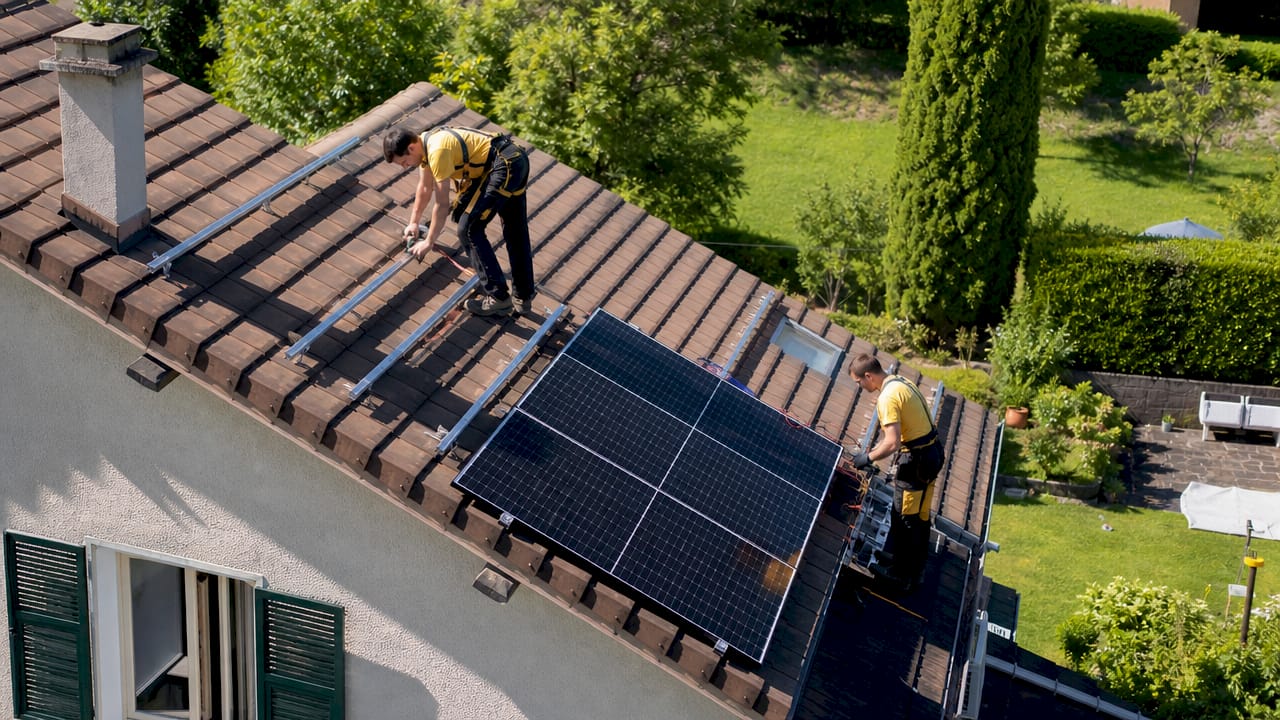 Des techniciens sont en train de poser des panneaux solaires sur le toit d’un bâtiment.