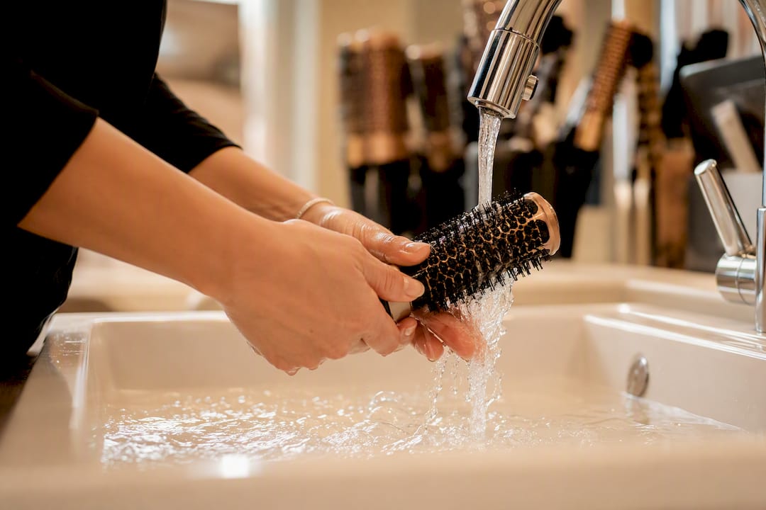 Mains en train de rincer les poils d'une brosse ronde