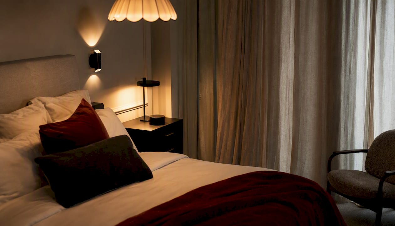 Ambiance chaleureuse et raffinée grâce à un éclairage tamisé en superposition dans un coin de chambre élégant.