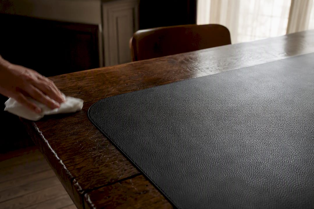 Set de table en cuir grainé posé sur une table en bois brut.