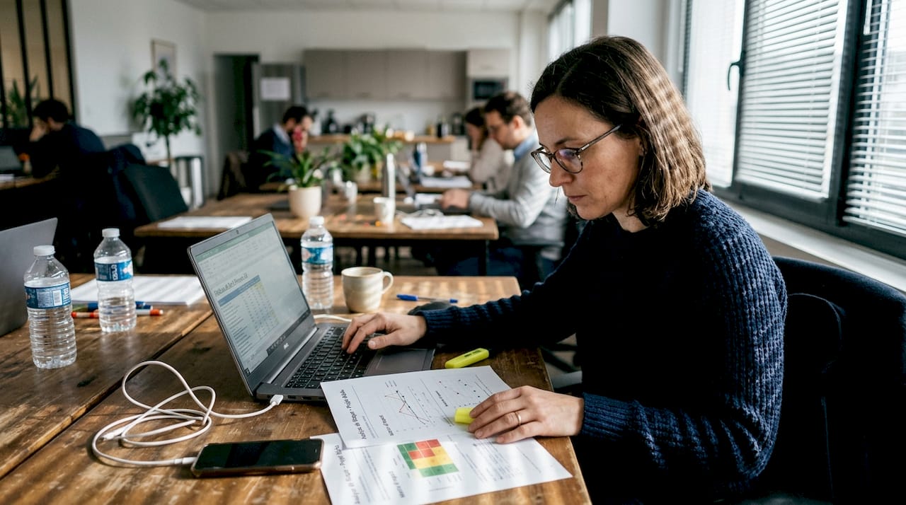 Une collaboratrice met à jour un tableau de suivi des risques à son poste de travail.
