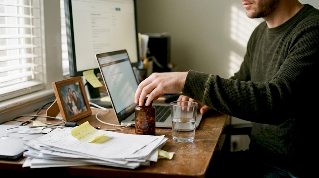 Man choosing red reishi capsules at desk