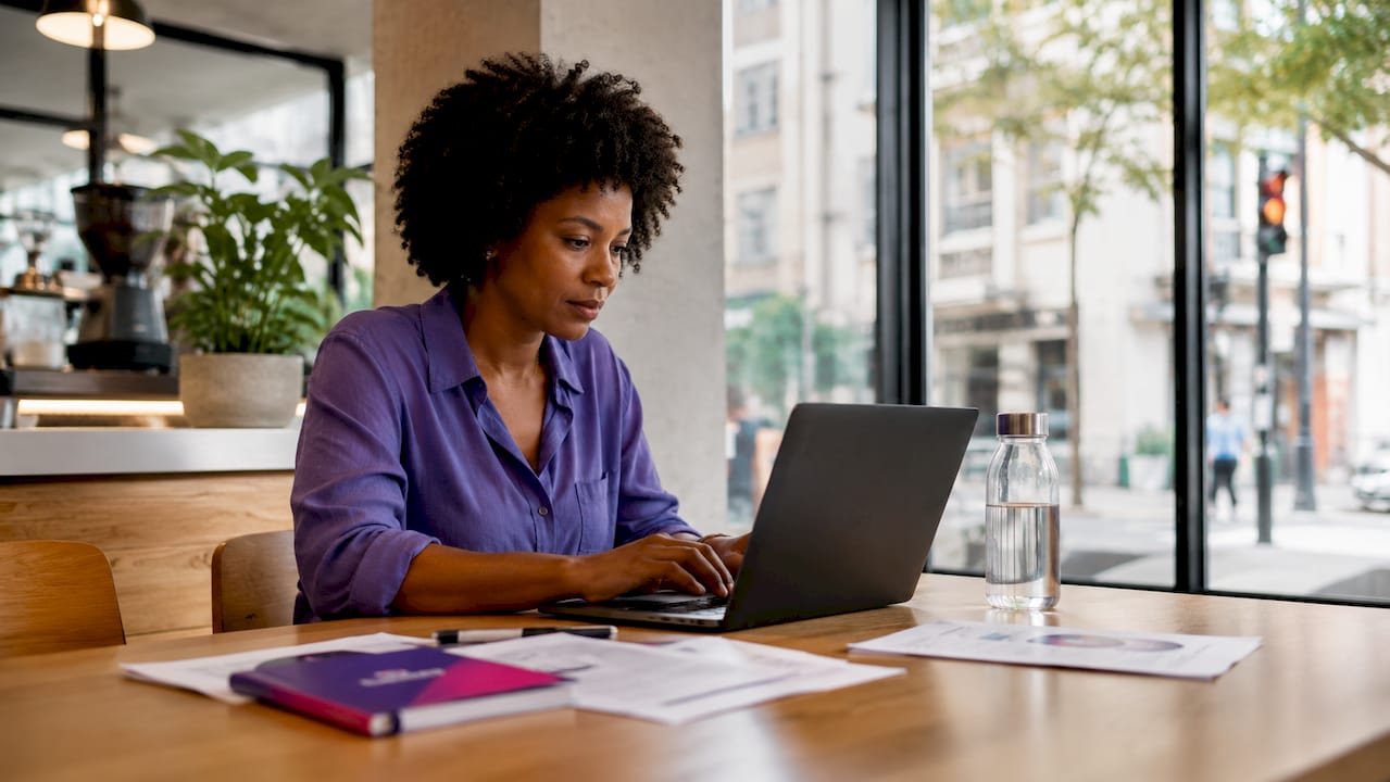 Une femme concentrée sur la gestion de ses priorités numériques depuis son ordinateur portable.