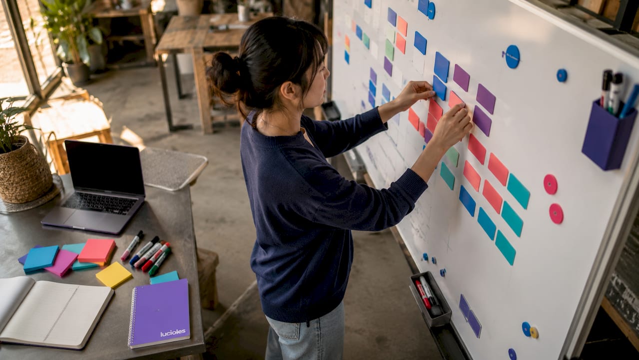 Qu'est-ce qu'un stack technologique marketing ? 1 Des mains organisent des étiquettes représentant des outils marketing sur un tableau, illustrant la mise en place d’une stratégie.