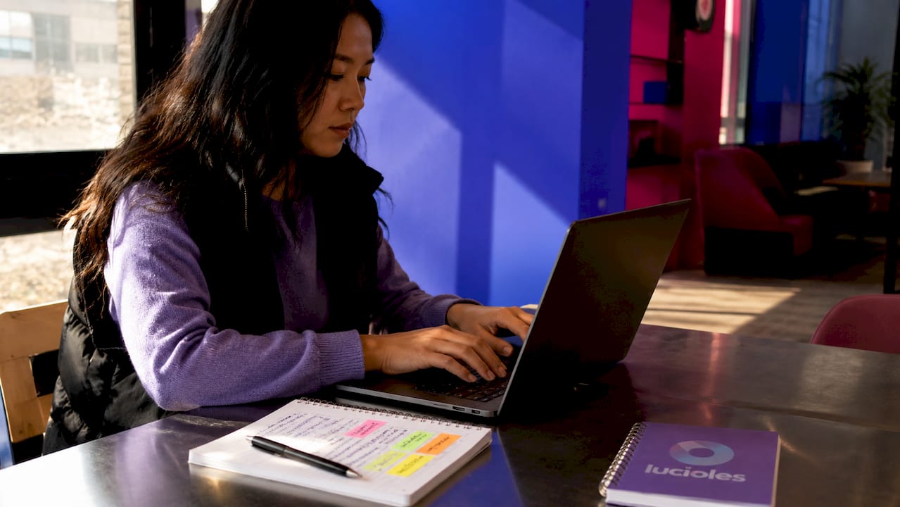 Neuromarketing : principes fondamentaux pour dirigeants 1 Une femme en train de travailler sur son ordinateur portable, installée dans un café baigné de lumière.